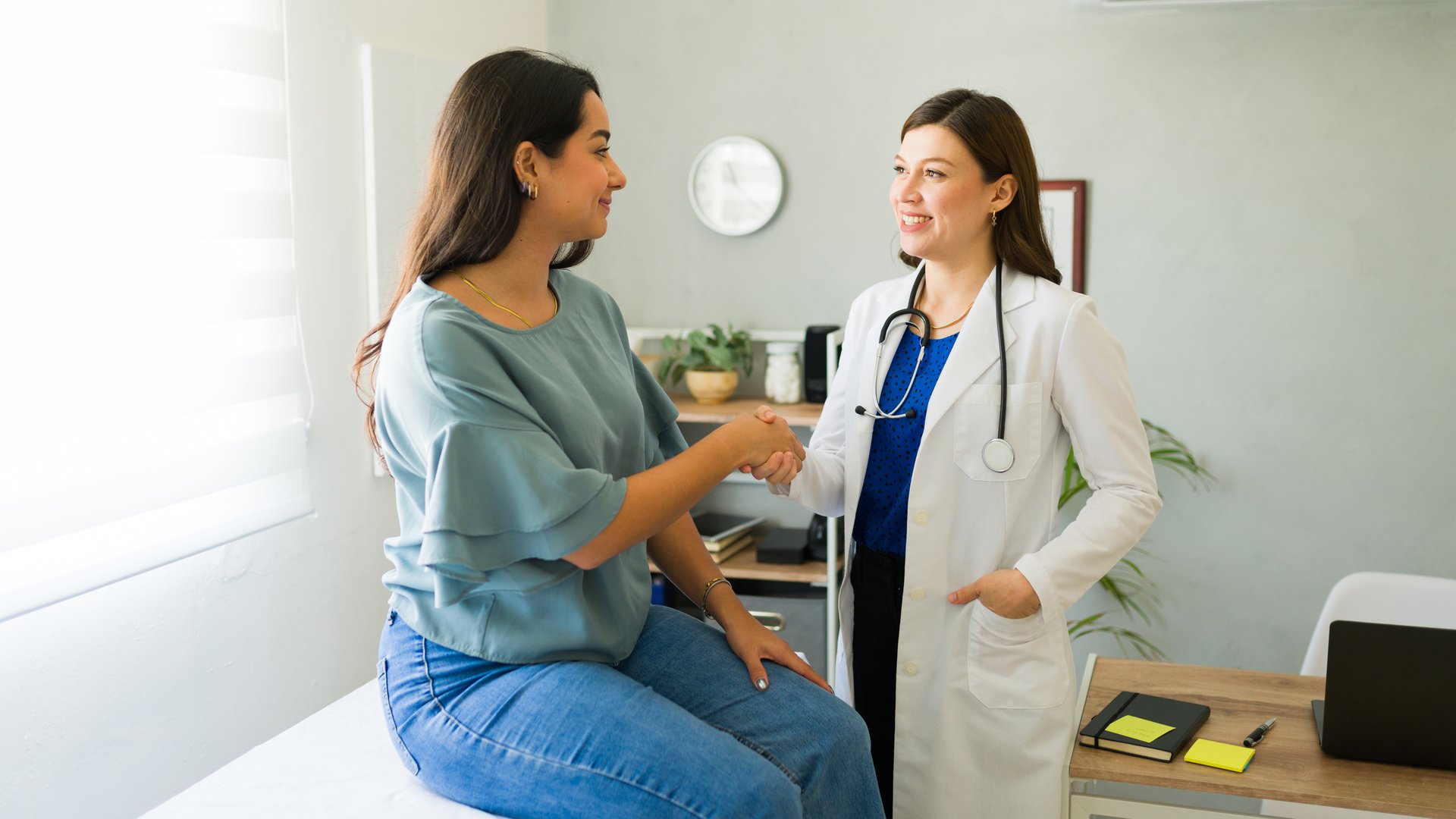 Female doctor happily shaking hands with her hispanic patient after a successful consultation